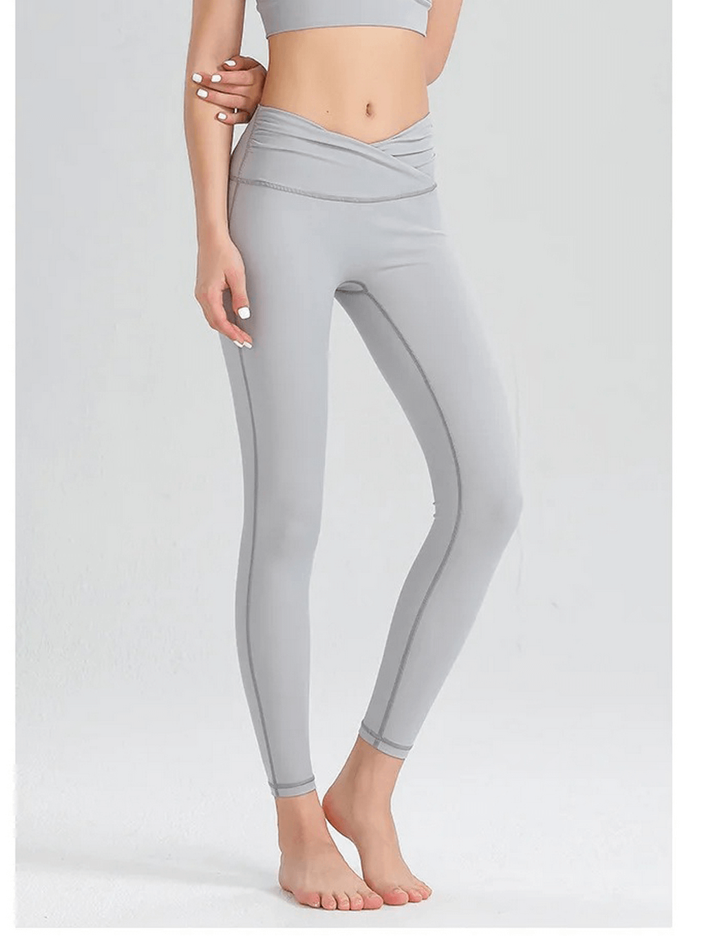 Woman wearing a grey spandex workout set, featuring a sleeveless top and leggings designed for breathability and performance.